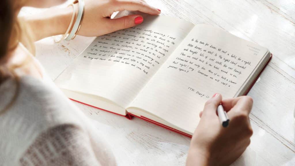 a woman using a pen and notebook to journal her everyday life.