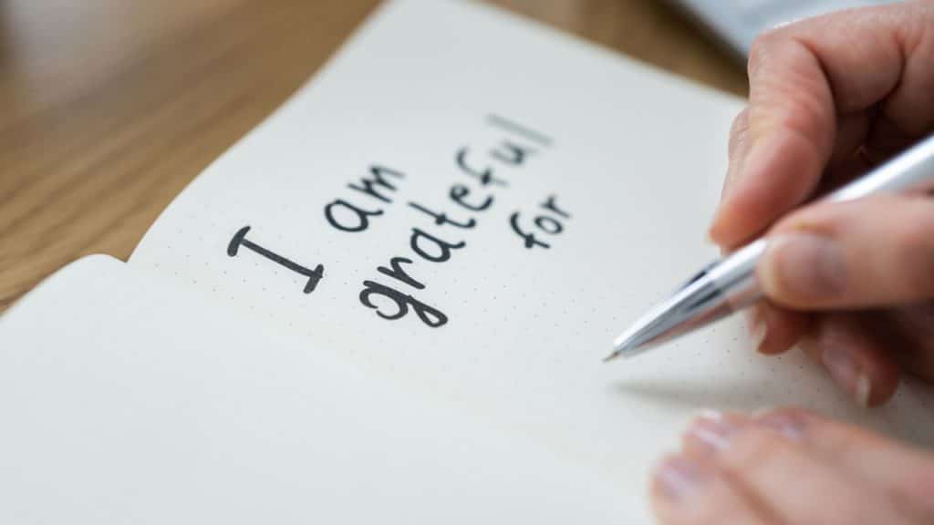 A woman holding a pen to write what she is grateful for.