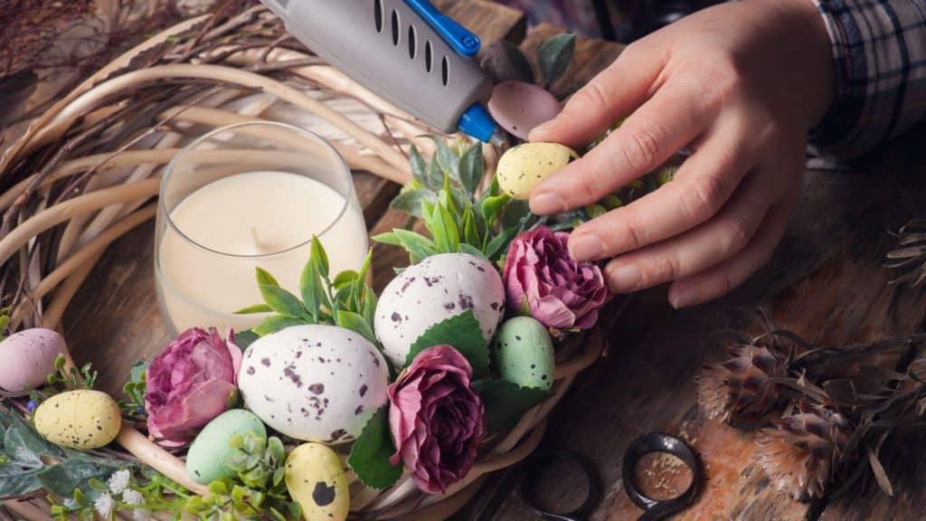 A person using a glue gun to make a DIY fall wreath.