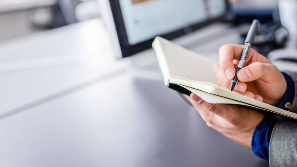 A person using a pen and paper to write some resume headlines