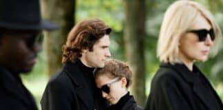 Portrait Of Young Couple Wearing Black Grieving Together And Embracing