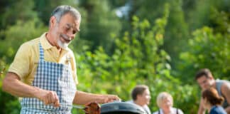 Family Having A Barbecue Party In Their Garden In Summer