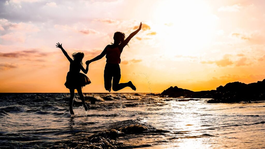 Photo showing two individuals jumping along the shoreline